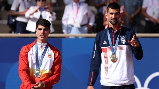 El medallista de oro Novak Djokovic de Serbia hace un gesto en el podio con el medallista de plata Carlos Alcaraz de España. (REUTERS)