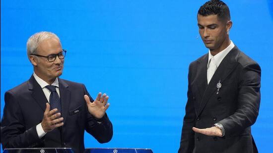 Giorgio Marchetti, de la UEFA, observa a Cristiano Ronaldo presionar un botón para proceder con el sorteo de la Liga de Campeones en Mónaco. (AP)