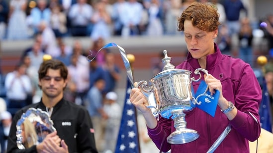 Jannik Sinner, de Italia, sostiene el trofeo del campeonato mientras Taylor Fritz, de Estados Unidos, observa. (AP)