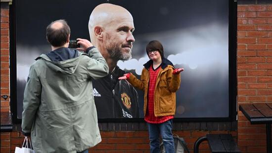 Un visitante reacciona mientras posa frente a una foto del recién despedido entrenador del Manchester United, Erik ten Hag. (AFP)