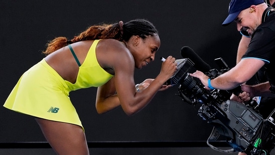 Coco Gauff de Estados Unidos autografia la pantalla de una cámara de televisión después de derrotar a Jodie Burrage de Gran Bretaña en su partido de segunda ronda en el campeonato de tenis del Abierto de Australia en Melbourne (AP)