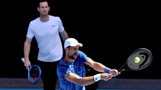 El serbio Novak Djokovic (derecha) regresa mientras el entrenador Andy Murray observa durante una sesión de entrenamiento antes del torneo de tenis Abierto de Australia. (AFP)