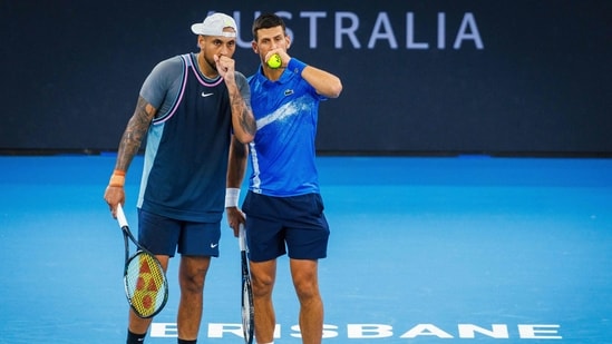 El serbio Novak Djokovic (dcha.) habla con el australiano Nick Kyrgios antes de anotar un punto durante un partido de dobles masculino. (AFP)