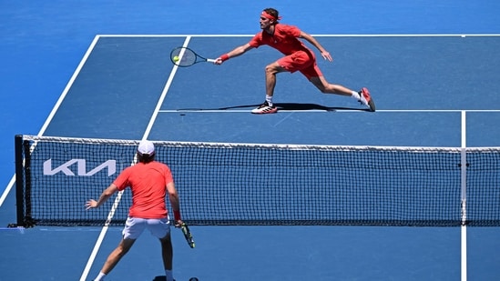 El griego Stefanos Tsitsipas (arriba) devuelve el balón al estadounidense Alex Michelsen durante su partido individual masculino en el segundo día del torneo de tenis Abierto de Australia en Melbourne. (AFP)