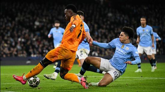 Vinicius Junior (L) del Real Madrid lucha por el balón con Rico Lewis de Manchester City durante su partido de la Liga de Campeones. (AFP)